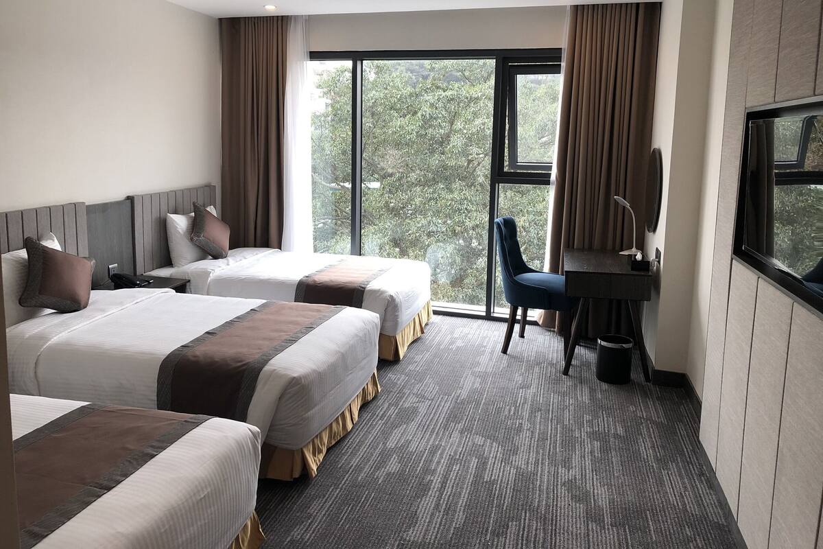A hotel room with two beds, a desk, and a chair.