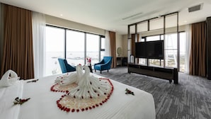 A hotel room with a large bed, a TV, a balcony with a view, and a desk with a chair. - Muong Thanh Grand Bai Chay Hotel (Bai Chay)