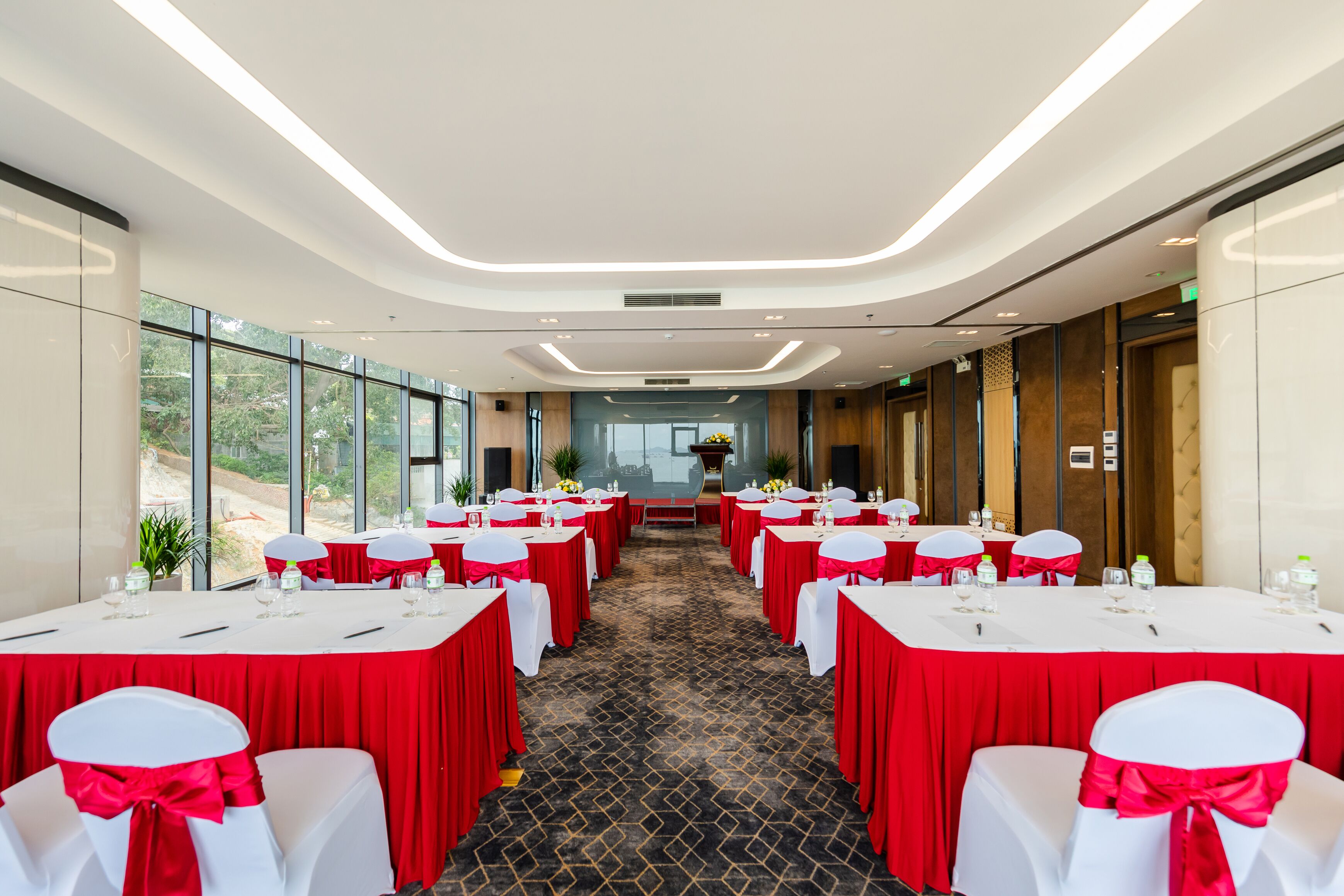 A conference room with tables set for a meeting, large windows, and a carpeted floor.