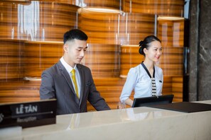 A reception desk with a sign that reads "LE TAN Reception". - Muong Thanh Grand Bai Chay Hotel (Ha Long)