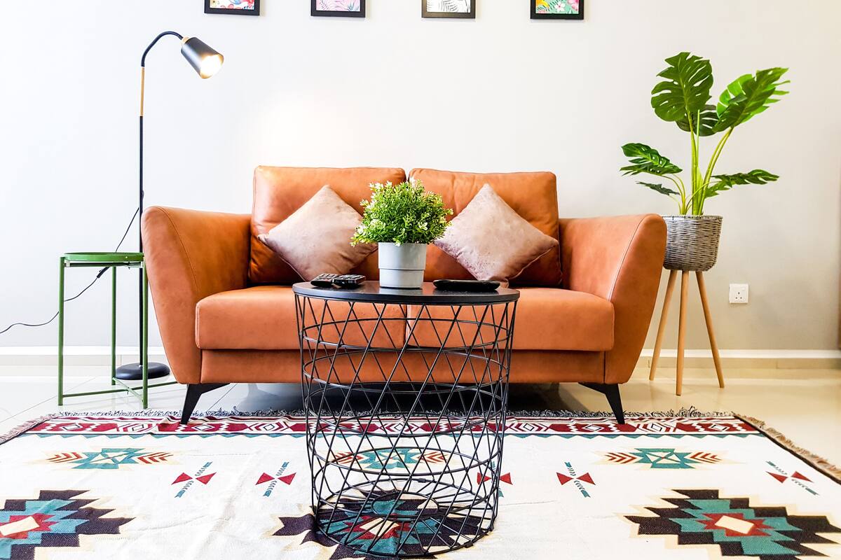 A modern living room with a leather sofa, a round coffee table, a floor lamp, and a patterned rug.