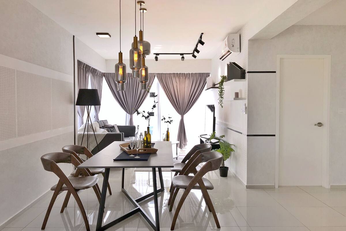 A modern dining area with a central table, four chairs, and pendant lighting.