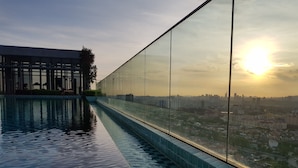 Ein Infinity-Pool auf dem Dach mit Blick auf die Stadt, Glasgeländern und moderner Bauweise.