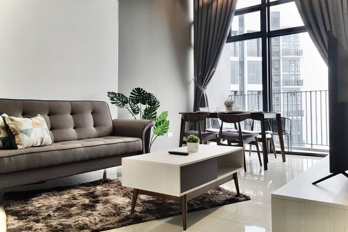 A modern living room with a sofa, coffee table, and dining area.