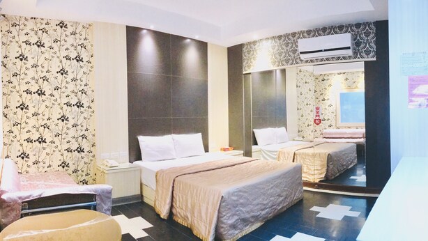 Une chambre d’hôtel avec deux lits, un grand miroir, un téléviseur à écran plat et une petite table.