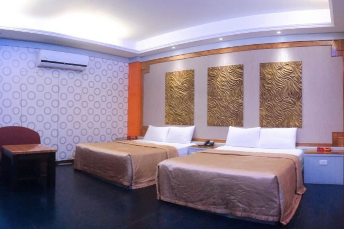 A hotel room with two beds, a desk, and a chair.