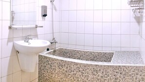 Une salle de bain équipée d’un lavabo, d’un miroir, d’une douche et d’un porte-serviettes.