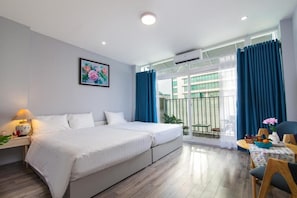 A modern hotel room with a large bed, a desk with a lamp, a dining area with a table and chairs, and a balcony with blue curtains. - The Art - Hung Viet near Truc Bach lake (Hanoi)