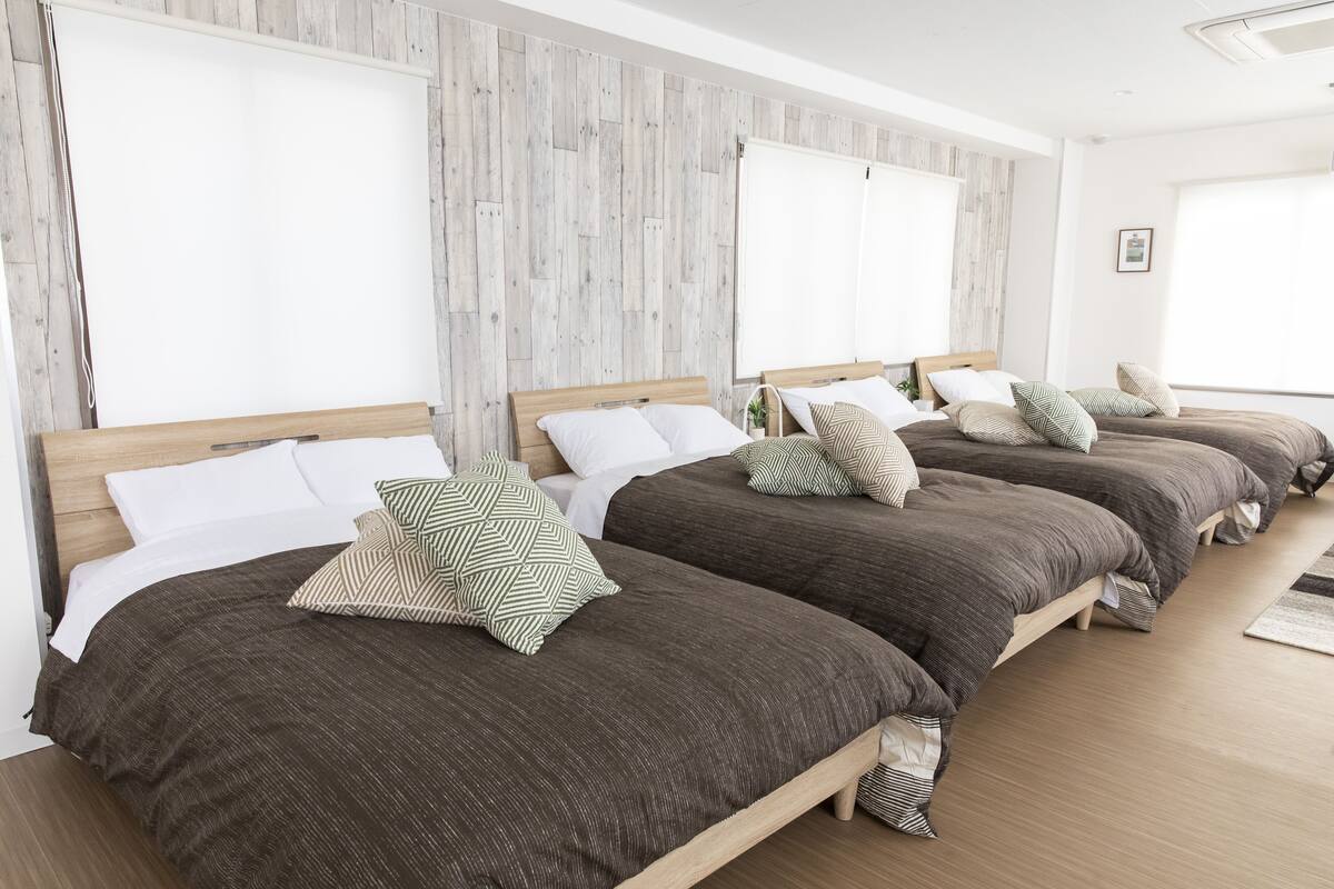 A hotel room with three beds, each with a wooden headboard and brown bedding.