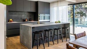 A modern kitchen with a central island, bar stools, and a view of the outdoors. - Onetangi Oasis - fabulous home with pool & great views! (Onetangi)