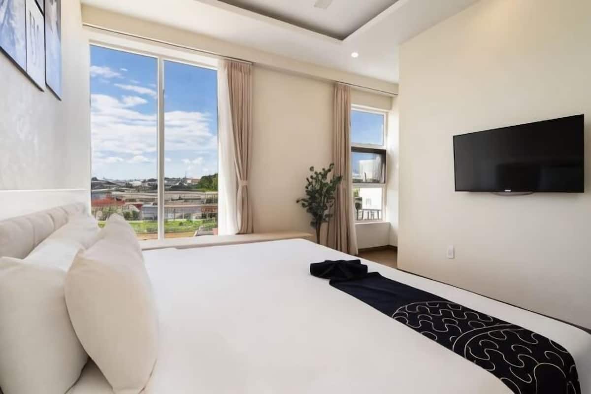 Ein Hotelzimmer mit einem großen Bett, einem an der Wand befestigten Fernseher und einem Balkon mit Blick.