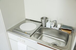A kitchen with a built-in microwave, a stainless steel sink, a kettle, and a soap dispenser. - River Villas Hiroshima (Hiroshima)