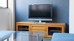 En tv-apparat står på ett träskåp, och bakom den finns en vägg med ett mönster.