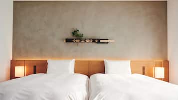 Una cama doble con sábanas blancas, cabecera de madera y lámparas de noche.