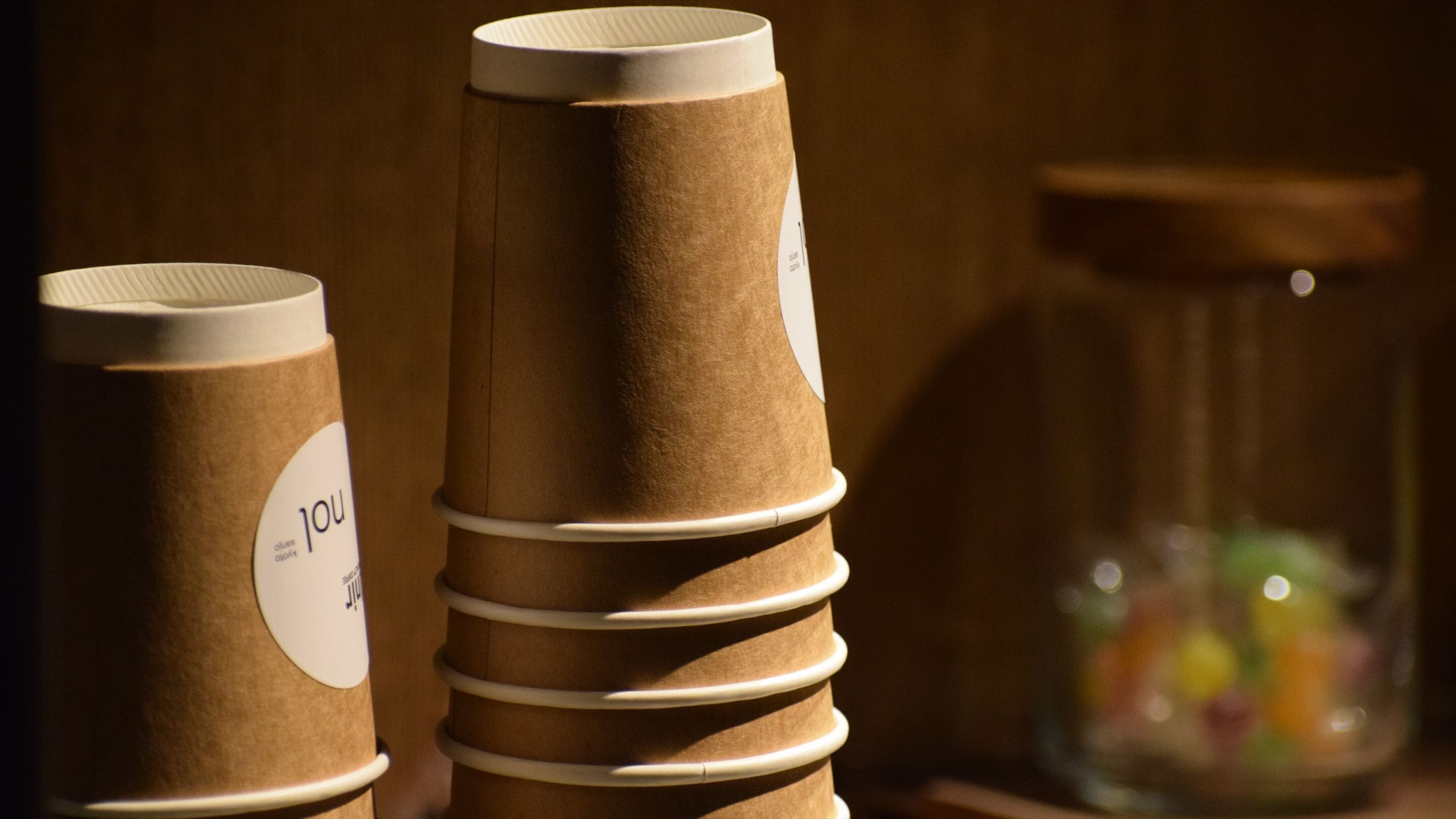 A stack of paper cups with a label, placed next to a jar of candies.