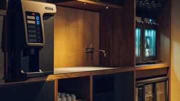 A coffee machine with a digital display, a wooden cabinet, a sink, and a television.