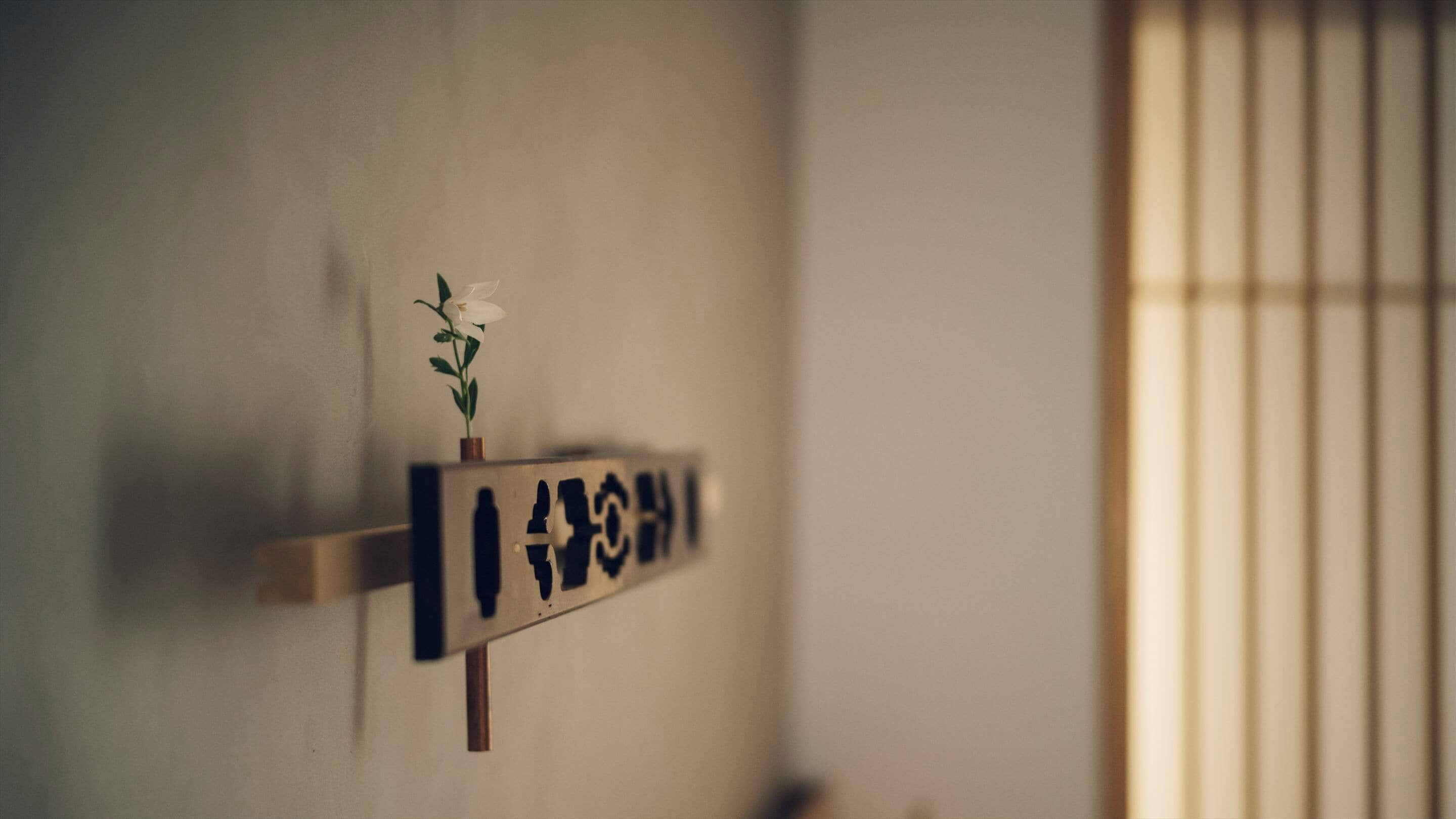 A sign with a plant on a wall, a window with vertical blinds, and a door.