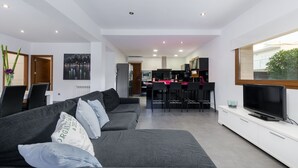 A modern living room with a sofa, TV, and dining area. - YourHouse Cardinal (Can Picafort)