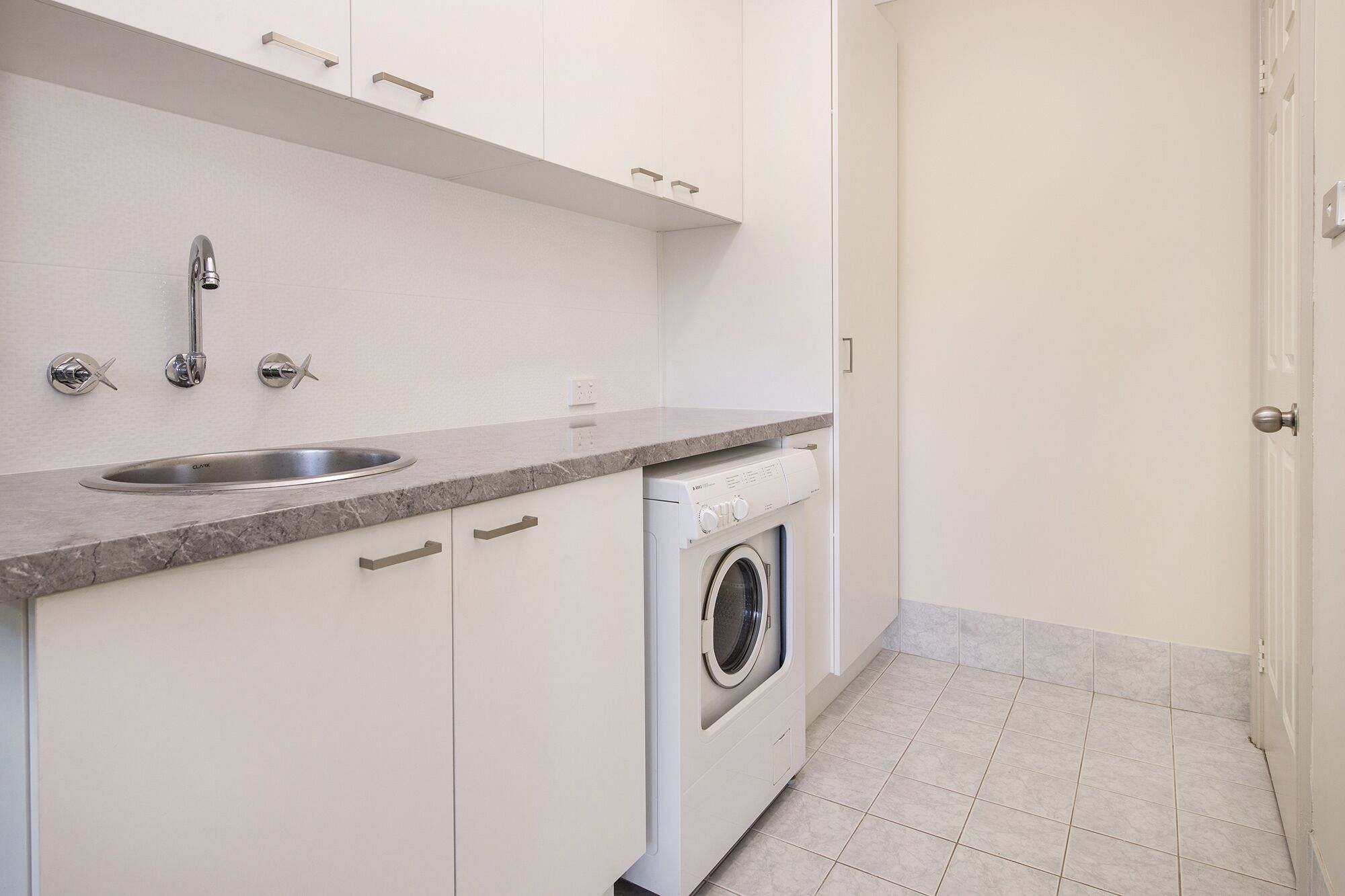 A compact kitchen with a sink, faucet, and a built-in washing machine.