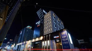Un hotel con un llamativo letrero de 'Westin', varios pisos y un anuncio iluminado de gran tamaño para la 'Gran Inauguración' de una cafetería.