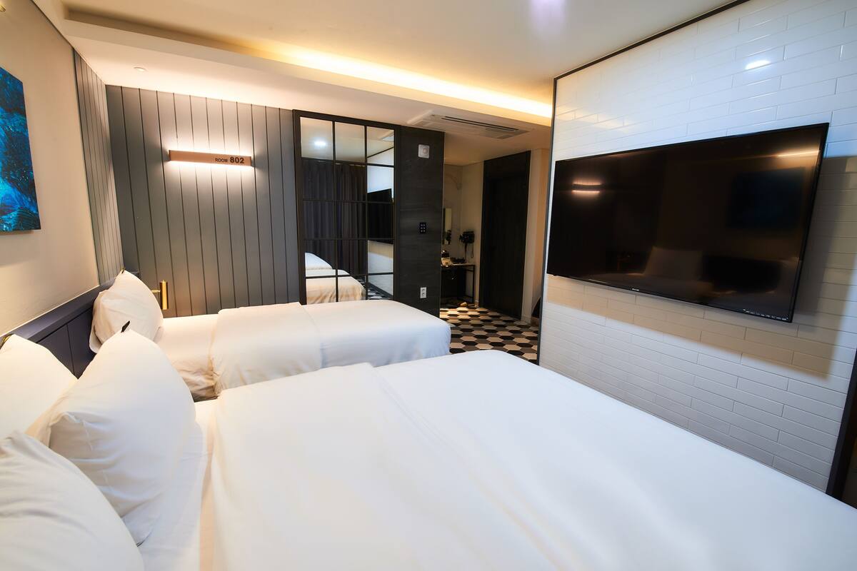 Habitación de hotel con dos camas, un televisor y un mostrador de recepción.