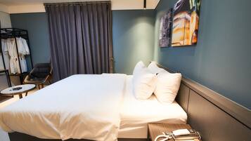 A hotel room with a large bed, a chair, a small table, and a wall-mounted artwork.