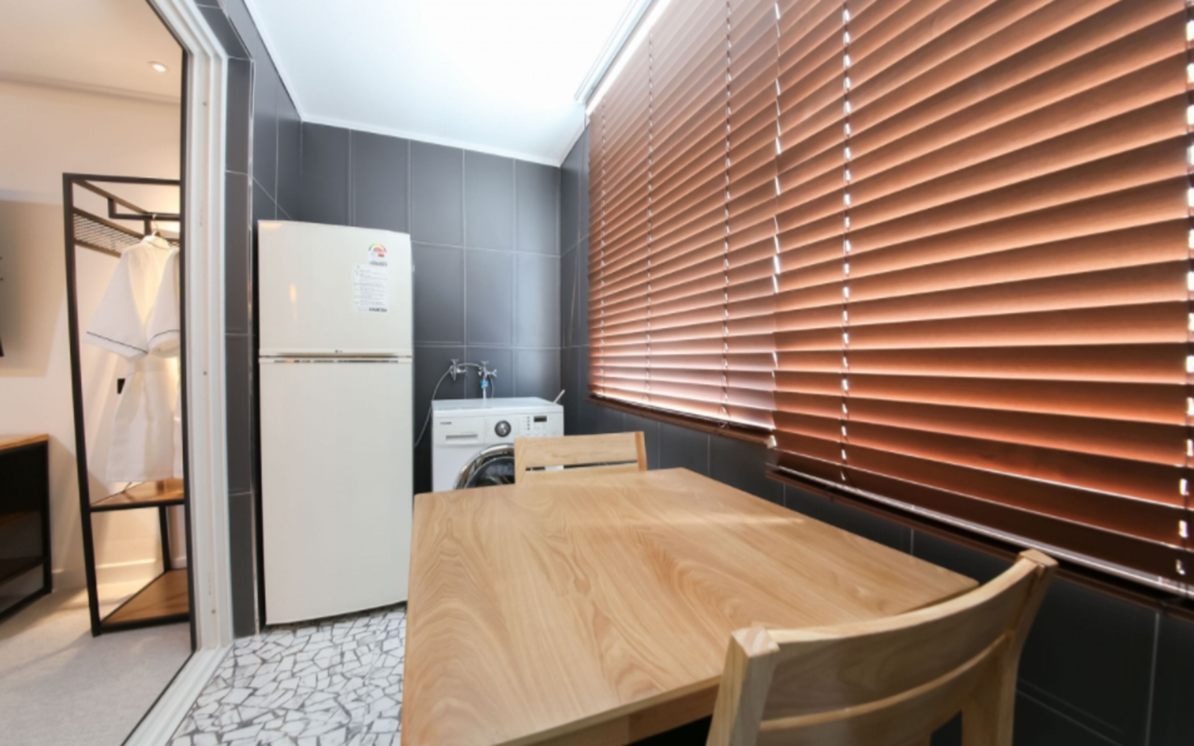 Una cucina compatta con frigorifero, lavatrice e un tavolo da pranzo in legno.