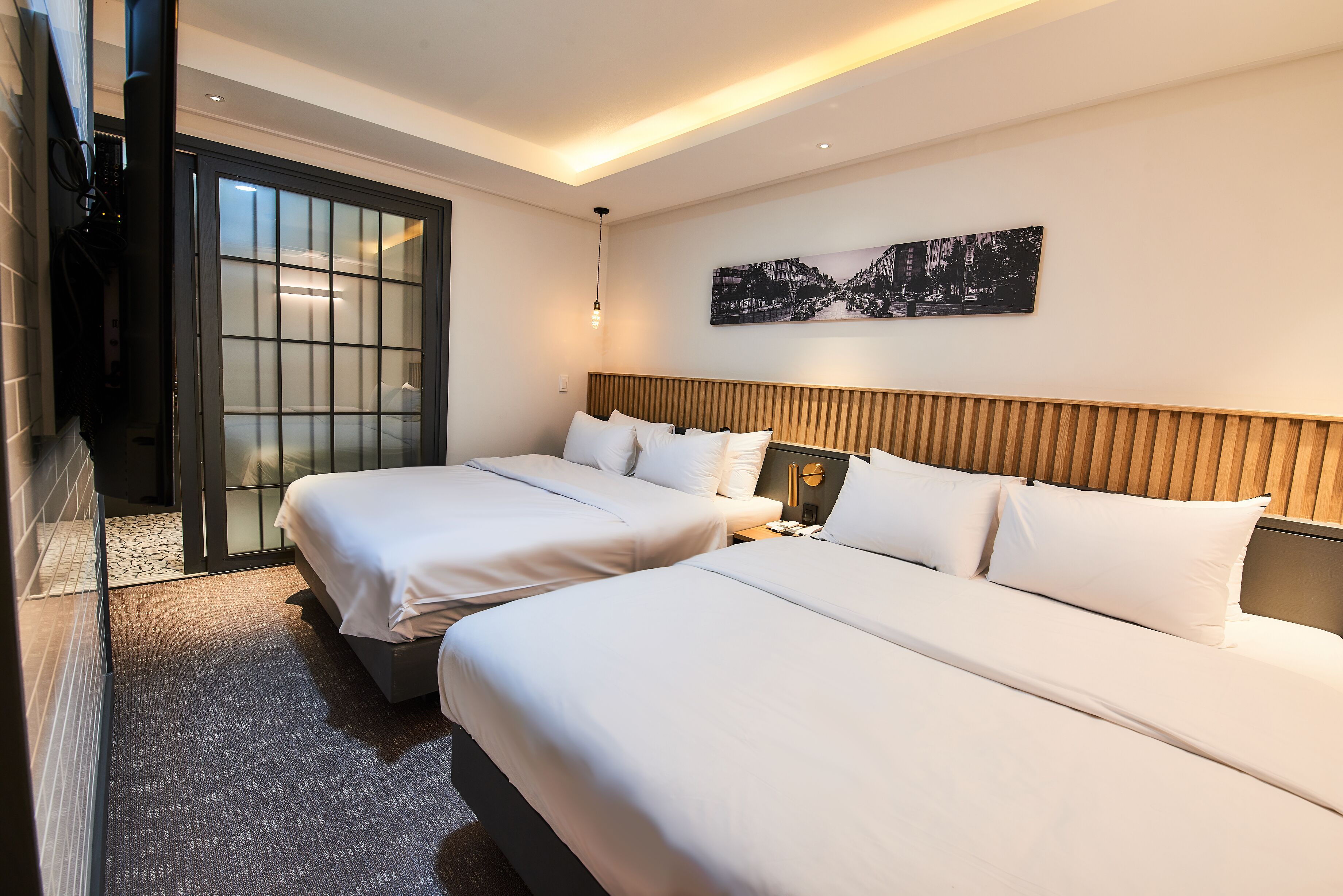Une chambre d’hôtel avec deux lits, une grande fenêtre et une œuvre d’art accrochée au mur.