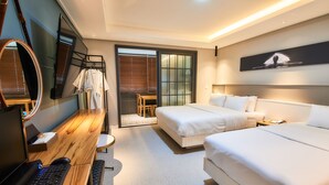 Una habitación de hotel moderna con un escritorio de madera, dos camas, un espejo grande y un ventanal corredero que da a un balcón.