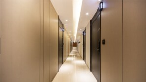 Un largo y estrecho pasillo de hotel con puertas a ambos lados y un suelo brillante y reflectante.