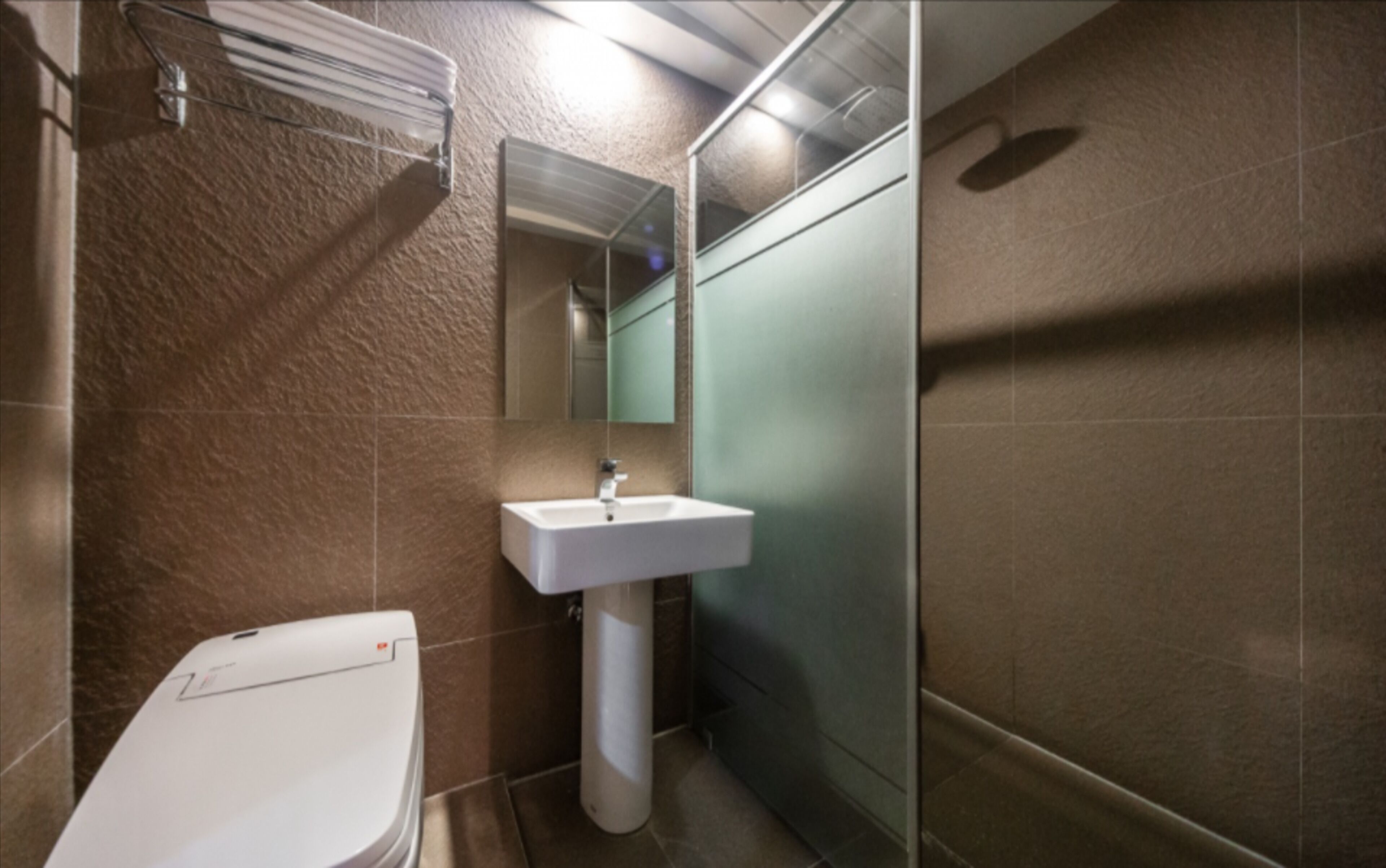 Baño con inodoro blanco, lavamanos y espejo.