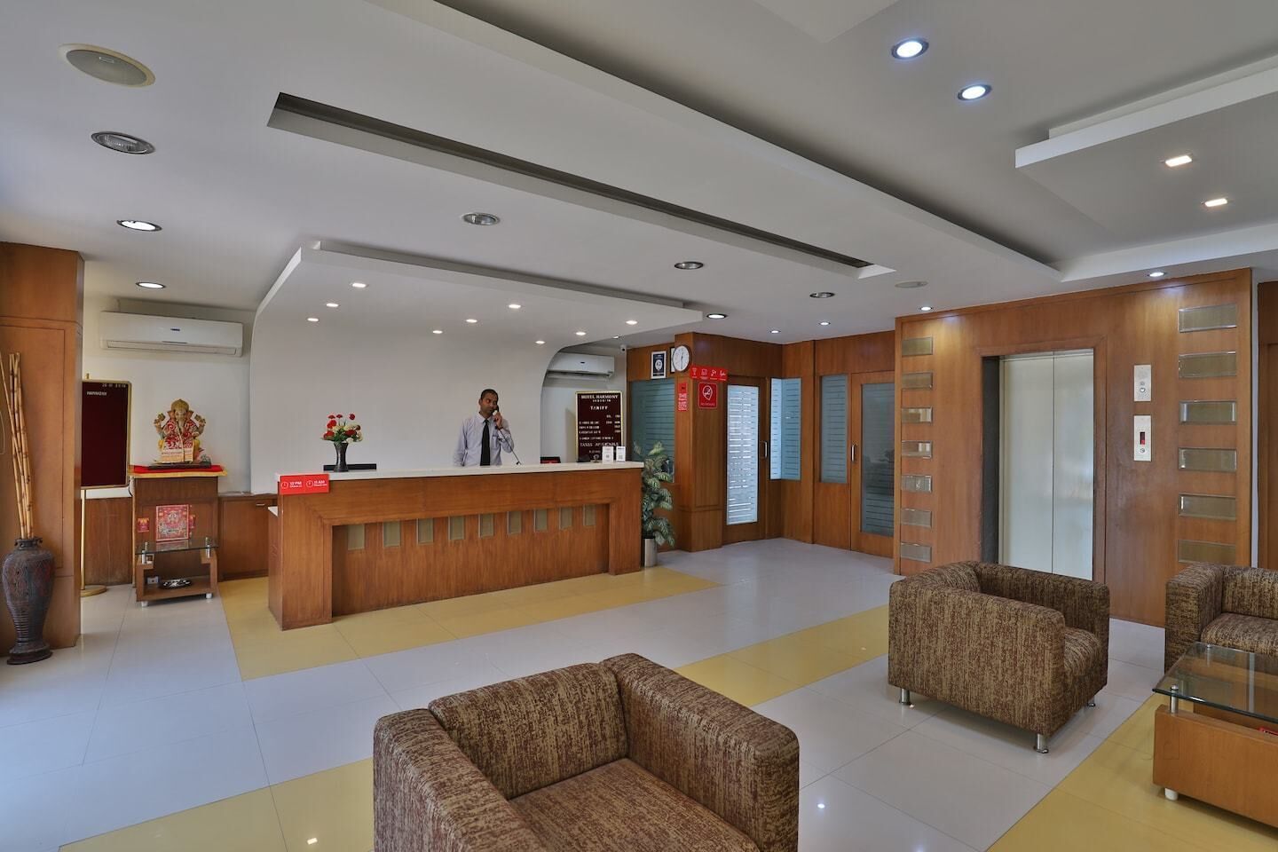 A hotel lobby with a reception desk, seating area, and an elevator.