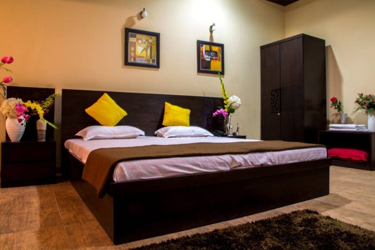A bedroom with a large bed, two nightstands, a wardrobe, and wall art.