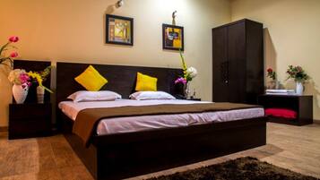 A bedroom with a large bed, two nightstands, a wardrobe, and wall art.