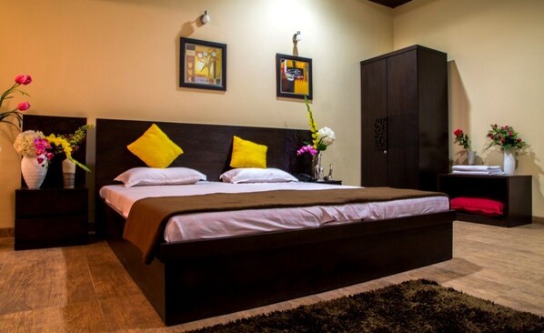 Un dormitorio con una cama grande, dos mesitas de noche, un armario y decoración en la pared.