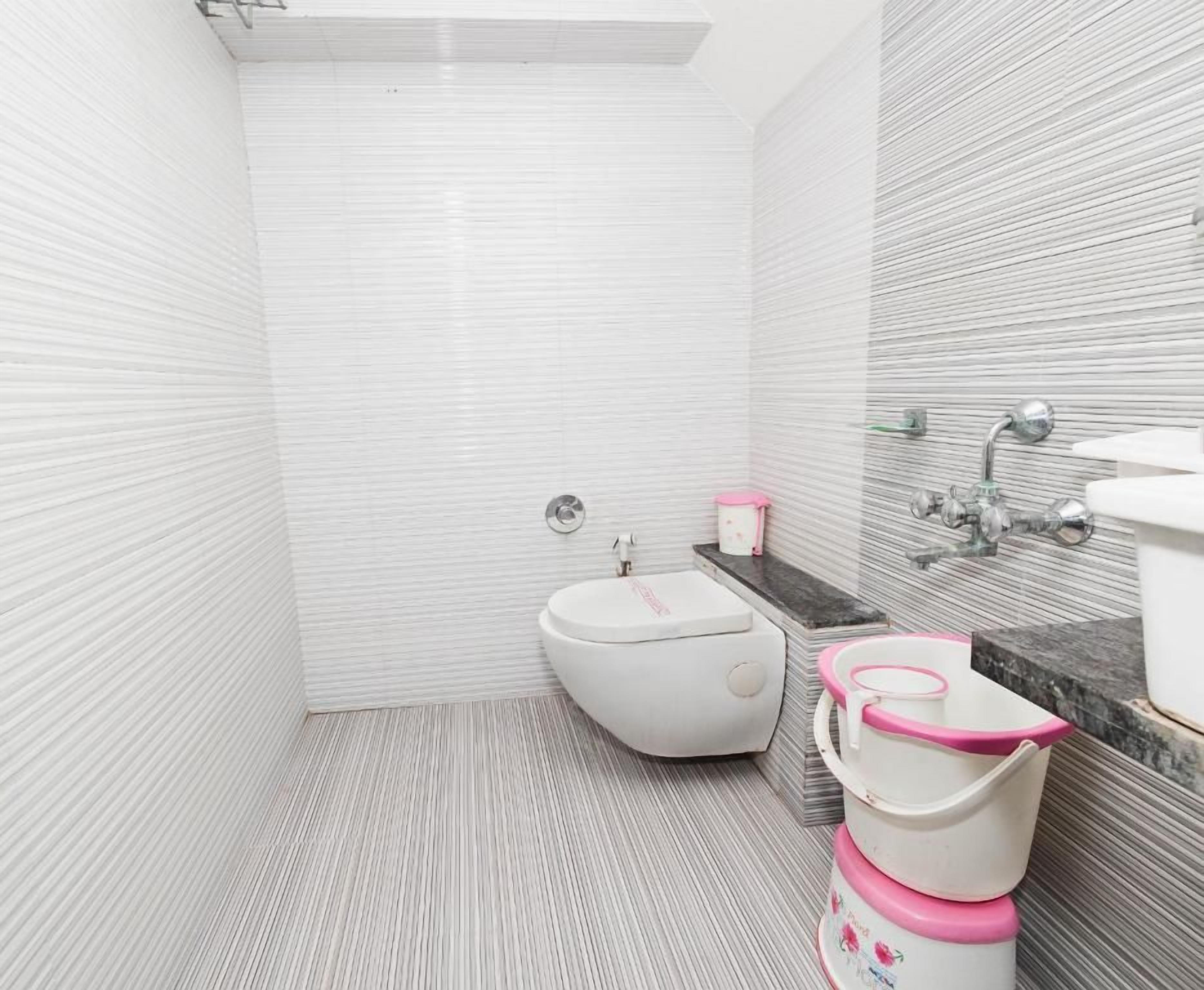A bathroom with a white toilet, a bidet, and a sink with a marble countertop.