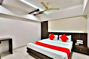 Un dormitorio moderno con cama, mesita de noche, escritorio y ventilador de techo.