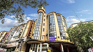 A multi-story hotel with a prominent tower and a sign for the Amber Hotel. - Hotel Amber (Vadodara)