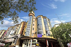 Un hotel de varios pisos con una torre destacada y un cartel que dice Amber Hotel.