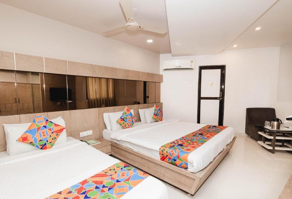 A hotel room with two beds, a desk, a chair, and a ceiling fan.