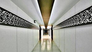 A corridor with patterned wall decorations and a tiled floor. - Hotel Amber (Vadodara)