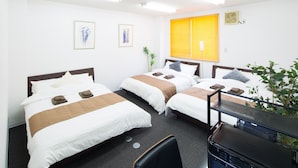 A hotel room with two beds, a desk, a chair, a plant, and artwork on the walls. - Sakamoto Building 6F (Osaka)