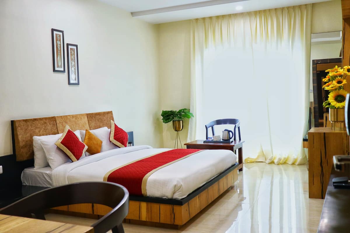 A hotel room with a bed, a desk, a chair, and a potted plant.