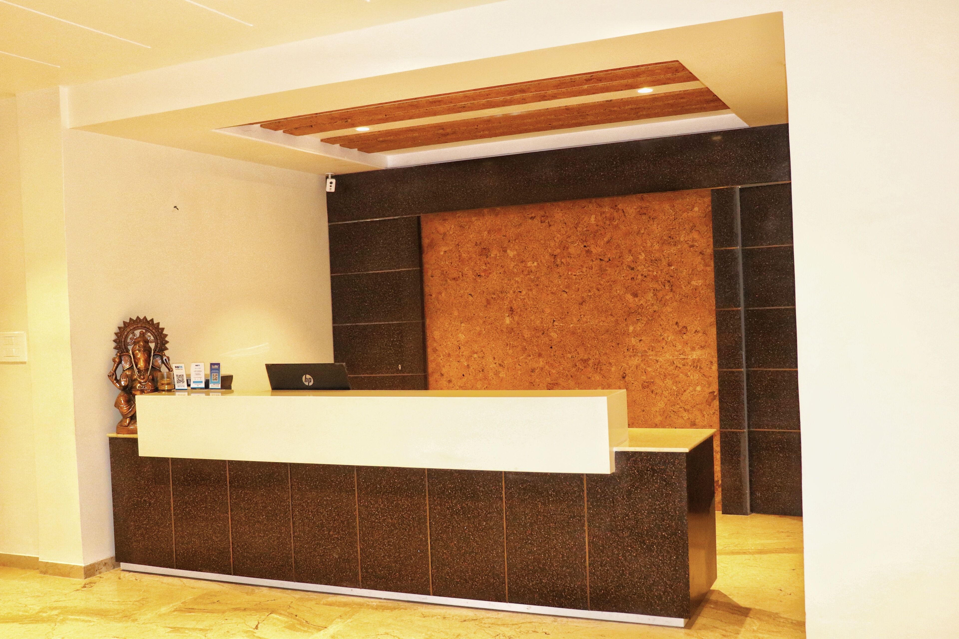 A reception desk with a laptop, a small statue, and a bulletin board.