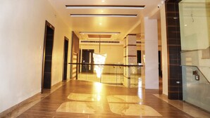 Un pasillo moderno de hotel con barandilla de vidrio, un candelabro y piso de mármol pulido.
