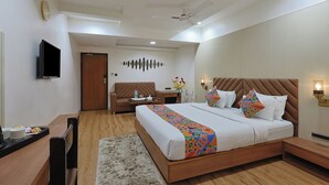 Una habitación de hotel moderna con una cama grande, un televisor de pantalla plana, un escritorio de madera y una zona de estar acogedora.