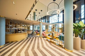 A modern hotel lobby with a bar area, seating, and large windows. - Wellton Riverside SPA Hotel (Riga)