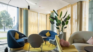 A modern living room with two sofas, a coffee table, and a floor lamp. - Wellton Riverside SPA Hotel (Riga)