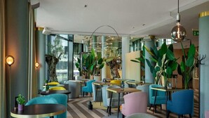 A modern interior with round tables and chairs, large potted plants, and a chevron-patterned floor.