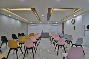 Ein Konferenzraum mit Reihen von Stühlen, einer Tafel und einer Uhr an der Wand.